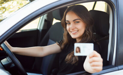 Lächelnde Frau im Auto zeigt Führerschein