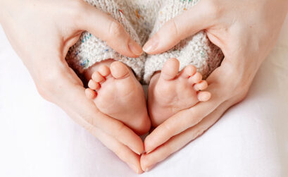 Mutter hat Hände in Herzform über Füße ihres Babys