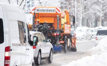 Orangenes Winterdienst Auto auf beschneiter Straße