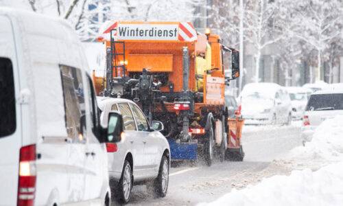 Orangenes Winterdienst Auto auf beschneiter Straße