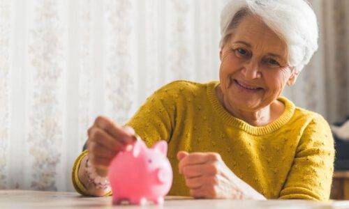 Lächelnde ältere Frau mit Sparschwein