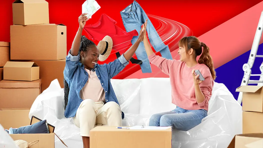 Zwei Frauen sitzen auf einem Sofa, umgeben von Kartons und Kleidung.