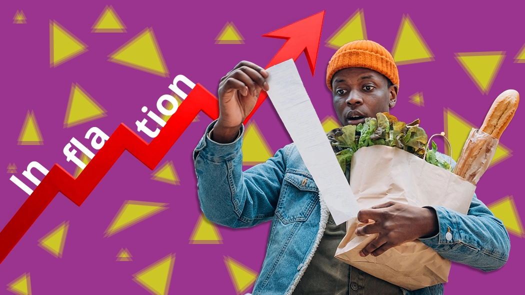 Ein Mann hält ein Schild mit der Aufschrift "Inflation" in einer öffentlichen Umgebung.