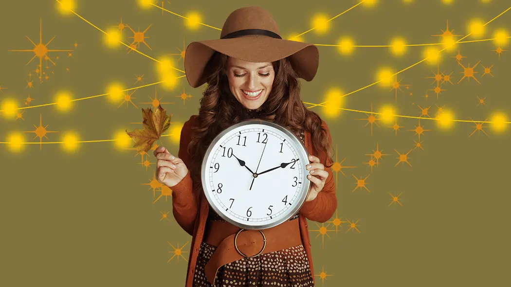 Eine Frau trägt einen Hut und hält eine Uhr, die mit einem Blatt dekoriert ist.