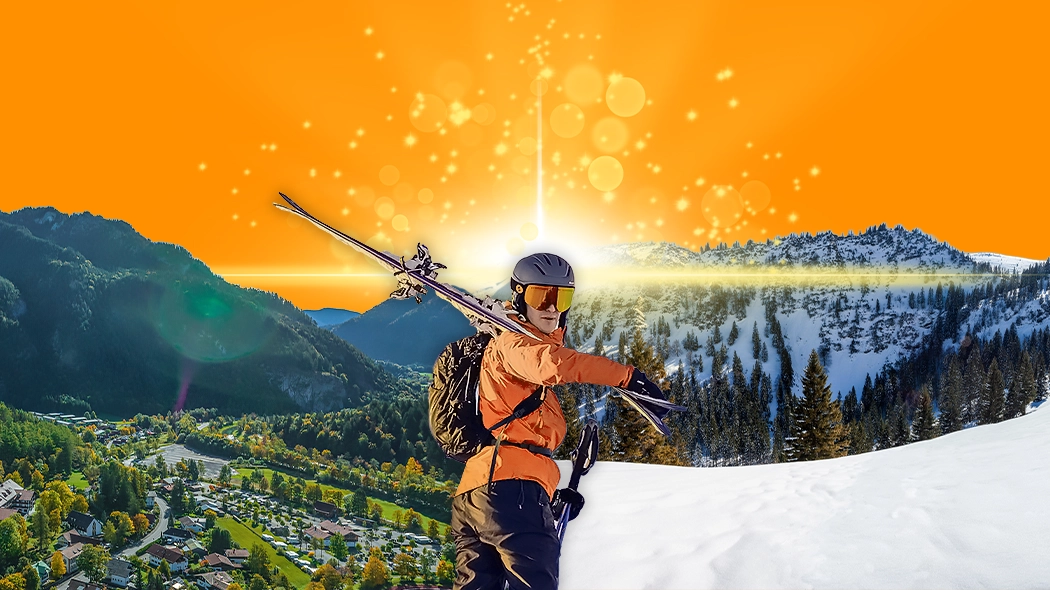 Ein Mann mit Skiern steht auf dem Gipfel eines Berges und blickt in die Ferne.