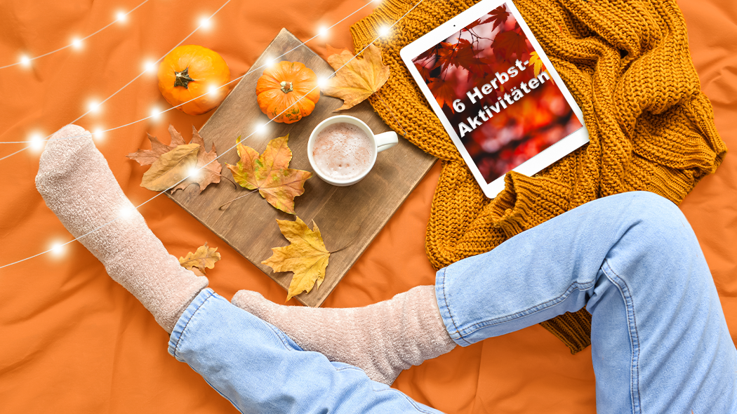 Gemütliche Atmosphäre im Herbst mit warmen Socken, Kürbissen, Blättern, Heißgetränk und einem Tablet mit dem Text „6 Herbst-Aktivitäten“.