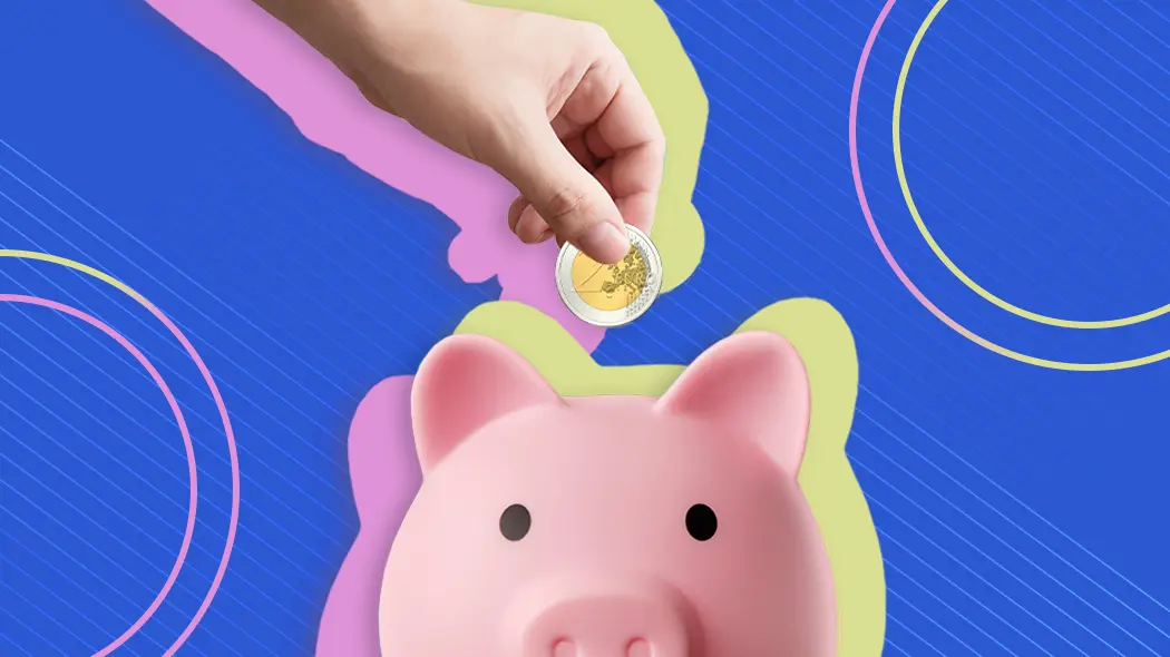 Hand wirft eine Euro-Münze in ein rosa Sparschwein zum Sparen und Vermögensaufbau.